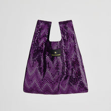 Purple sequin bag with a brand logo on a light gray background