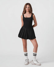 Woman wearing a black dress with white sneakers and striped socks on a white background