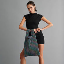 Woman holding a striped bag against a gray background

